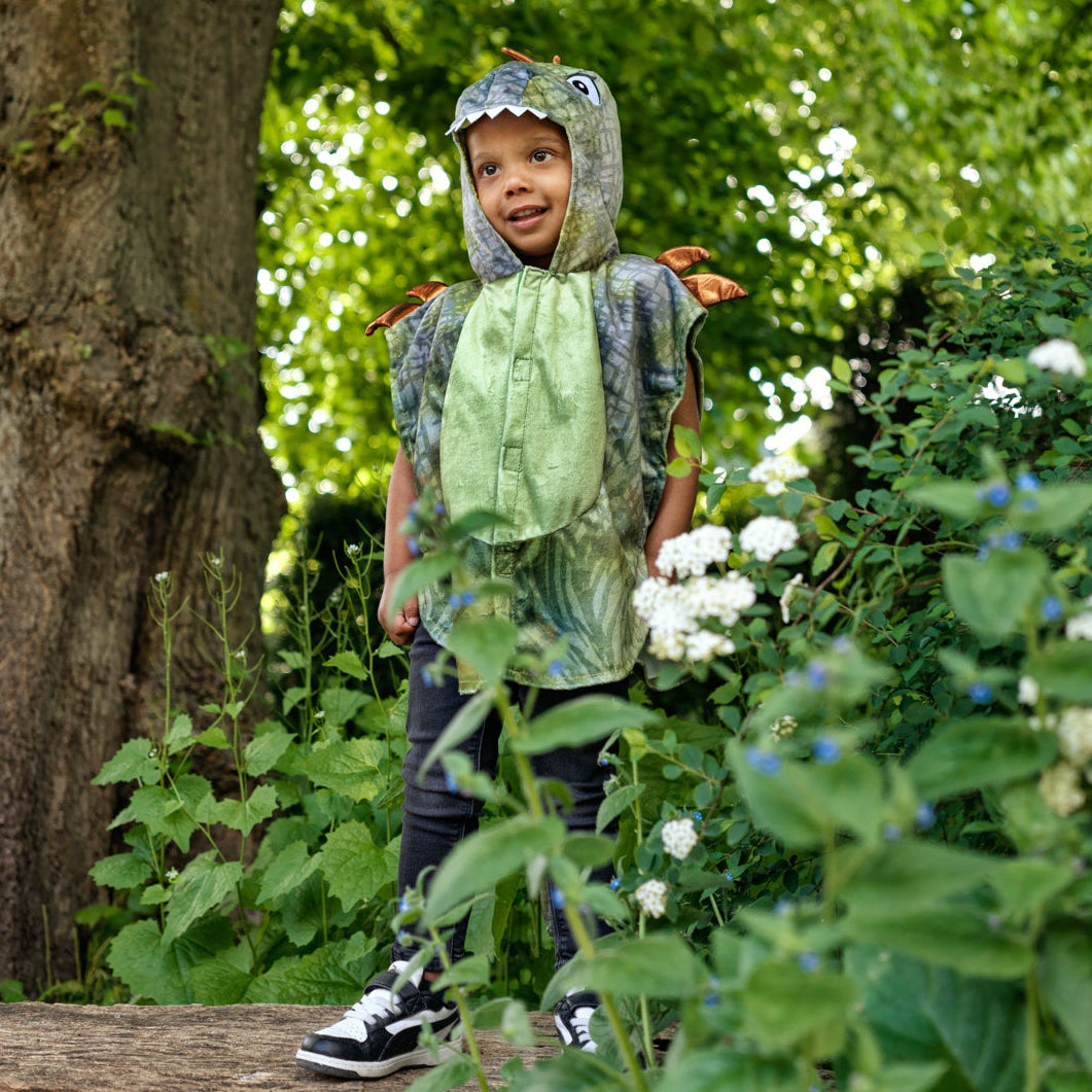 Child in a forest setting wearing a raincoat and standing among trees and flowers.