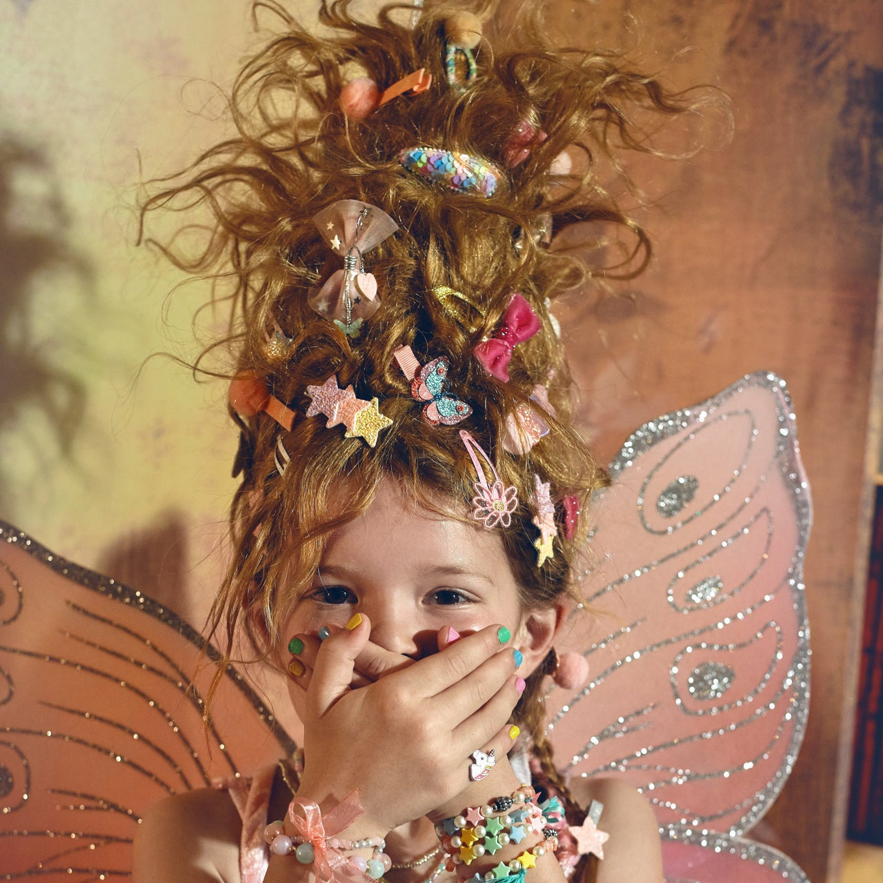Child with fairy wings and decorative hair accessories, wearing a colorful outfit.
